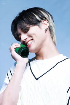 a young man holding a green object to his ear