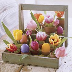 a wooden box filled with fake tulips on top of a table next to a couch