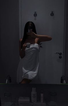 a woman taking a selfie in front of a bathroom mirror with the light on