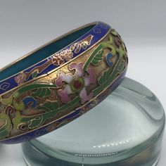 Beautiful enamel and metal cloisonné bangle bracelet. Still has its sticker and pouch! Some discolored metal, see photos. Brand: Lillian Vernon, Mount Vernon, NY Style: Intricate metal flowers and leaves with enamel detailing. Lined with gorgeous blue enamel. Has original pouch and sticker, marked with "Made in Hong  Kong Lillian Vernon Corp" and "Made in China for Lillian Vernon". Handmade Blue Metal Bangle, Vintage Blue Enamel Bracelets, Blue Enamel Bangle Gift, Blue Enamel Bracelet For Gift, Blue Enamel Bangle As A Gift, Blue Enamel Bangle Perfect As A Gift, Blue Enamel Bangle Bracelets, Blue Enamel Bangle, Handmade Blue Enamel Bracelets