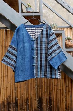 a blue shirt hanging up on a wooden rail next to a bamboo fence and stairs