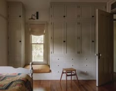 a bedroom with wooden floors and built in closets next to a bed that has a bench on it