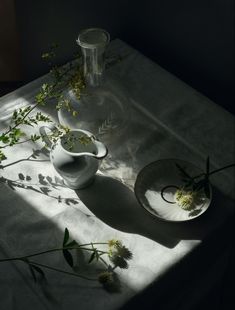 two vases with flowers in them sitting on a table next to a plate and bowl