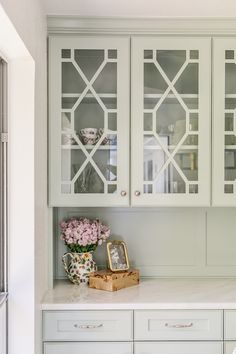 a kitchen with white cabinets and flowers in vases on the counter top next to it