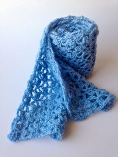 a blue crocheted scarf laying on top of a table