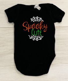 This adorable baby onesie is the perfect outfit for Halloween and fall. Available for infant, toddler and youth sizes. Your little one is sure to put a smile on anyone's face and is the perfect mix of cute and spooky! Comes in a black shirt with white cobwebs, orange and neon green lettering. Black Playful Bodysuit For Casual Wear, Black Onesie For Halloween Playtime, Cute Black Bodysuit For Playtime, Cute Fall Playtime Bodysuit, Cute Black Cotton Bodysuit, Halloween Onsies, Cute Halloween Onesie For Playtime, Black Halloween Onesie For Playtime, Cute Black Short Sleeve Onesie