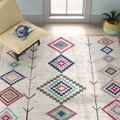 a white rug with multicolored diamonds on it in a room next to a chair