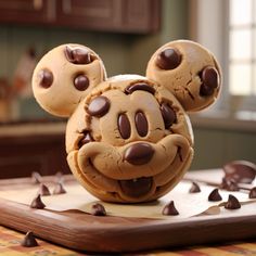 a mickey mouse cookie sitting on top of a cutting board with chocolate chips around it