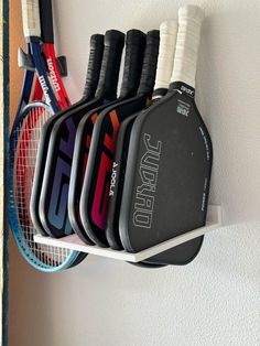 rackets and tennis balls are hanging on the wall next to a racket holder