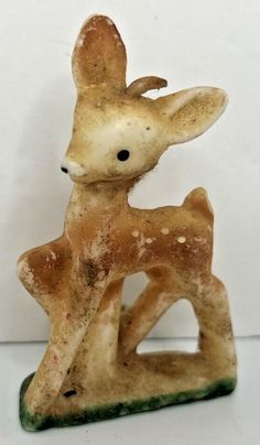 a ceramic deer figurine sitting on top of a white table next to a wall