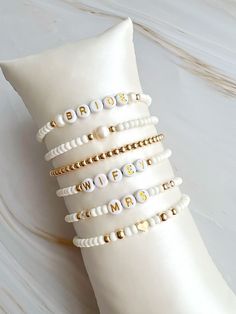 the bride's personalized bracelets are made from pearls and gold - plated beads