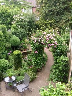 an outdoor patio with tables and chairs surrounded by greenery, shrubs and flowers in the background