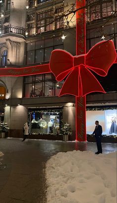 a giant red bow on the side of a tall building in front of a store