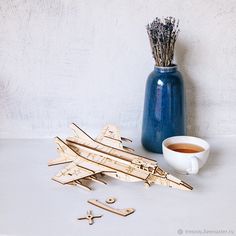 a cup of tea next to some wooden pieces and a vase with dried lavender in it