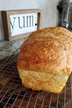 a loaf of bread sitting on top of a cooling rack next to a sign that says yum