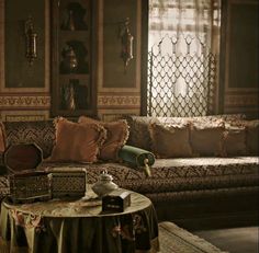 a living room filled with lots of furniture and pillows on top of a table in front of a window