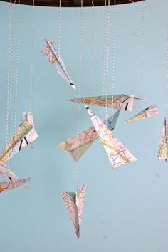 origami airplanes hanging from chains on a blue wall