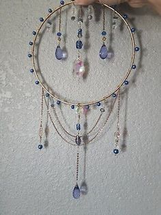 a person holding up a circular piece of jewelry with beads and chains hanging from it