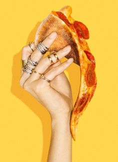 a hand holding up a piece of pizza