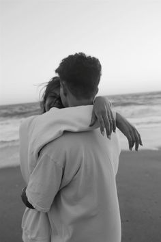 a man and woman hugging on the beach