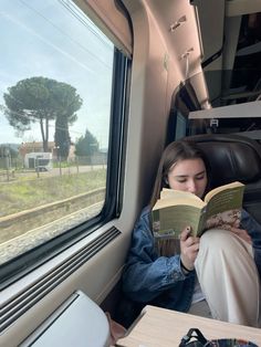 a woman reading a book while sitting on a train