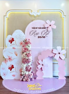 a pink and white wedding backdrop with flowers on the front, and an arch in the back