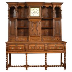 an old fashioned wooden desk with a clock on it's top and shelves below