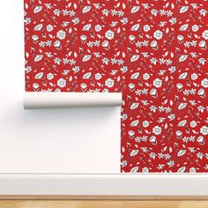 a red wallpaper with white flowers on it and a roll of paper next to it