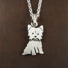 a small dog is shown on a silver plated necklace with a chain around it's neck