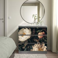 a dresser with flowers painted on it and a round mirror