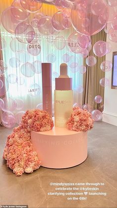 a display with pink flowers and bubbles in the background, including a bottle of deodorant