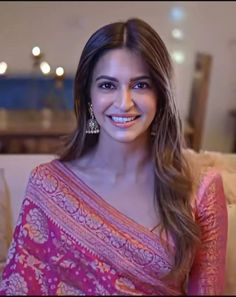 a woman in a pink sari sitting on a couch