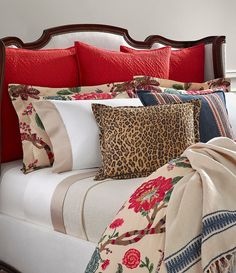 a bed with red pillows and leopard print on it