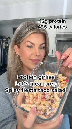 a woman holding a glass bowl filled with food and text that reads, protein girls let's meal prep spicy fiesta taco salad