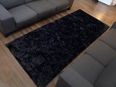 a living room filled with furniture and a black rug on top of a hard wood floor