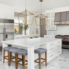 a kitchen with marble counter tops and white cabinets, two stools at the island