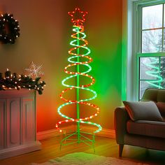 a christmas tree is lit up in the living room with green and red lights on it