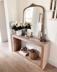 a wooden table topped with a mirror next to a vase filled with flowers and eggs