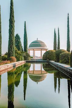 a gazebo surrounded by trees and water in the middle of a park with lots of greenery