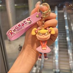 a hand holding a keychain with a cartoon character on it's side