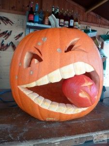 a carved pumpkin with its mouth open and an apple in it's mouth on a table