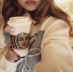 a woman holding a starbucks cup in her right hand and looking at the camera while wearing glasses