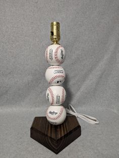 three baseballs stacked on top of each other in front of a gray background with a wooden base