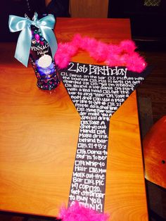 a birthday tie with pink feathers on it sitting on a table next to a cupcake