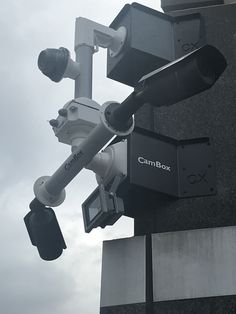 a camera attached to the side of a building next to a traffic light and street sign