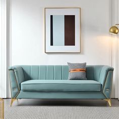 a blue couch sitting in front of a white wall with a framed painting on it