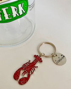 a keychain with a lobster on it sitting next to a can of pepsi