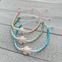 three bracelets with seashells and beads on wooden planked surface, closeup