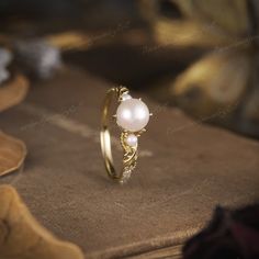 a pearl ring sitting on top of a table next to a cloth covered book and other items