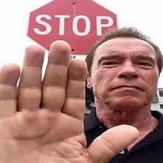 a man holding his hand up in front of a stop sign